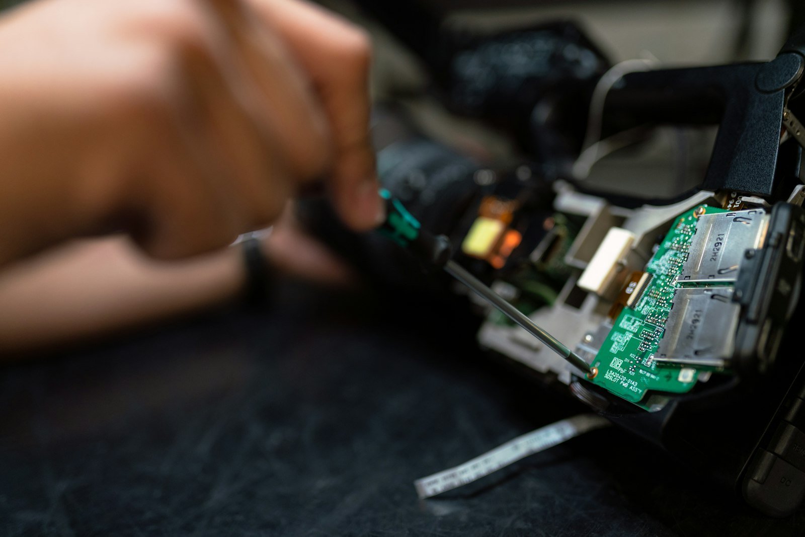 Repair technician holding a circuit board over an electronics workbench.