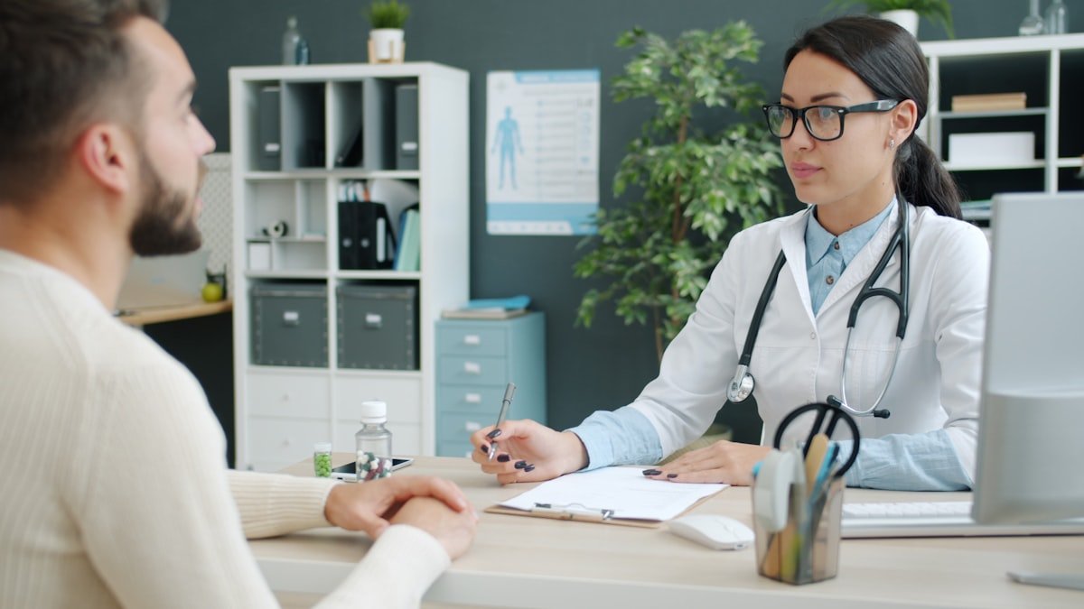 Doctor with stethoscope consulting a patient in a medical office.