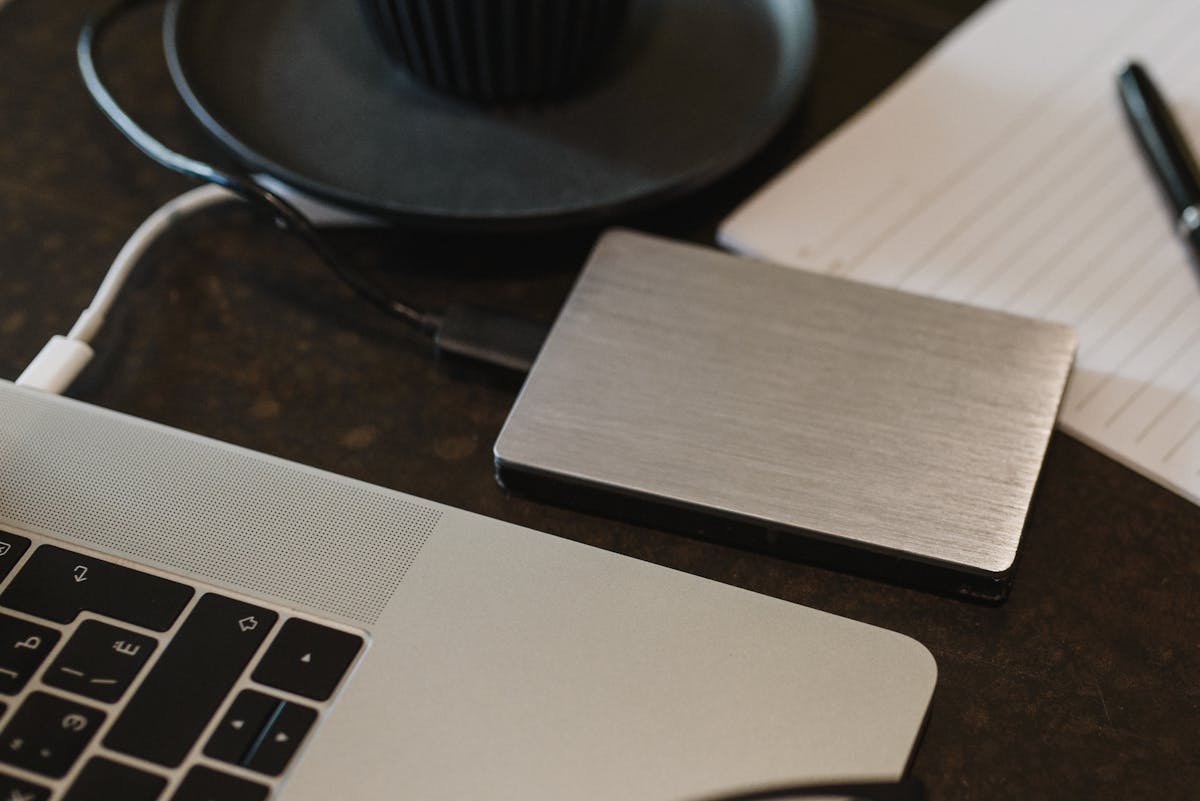 Portable external hard drive connected to a laptop on a desk.
