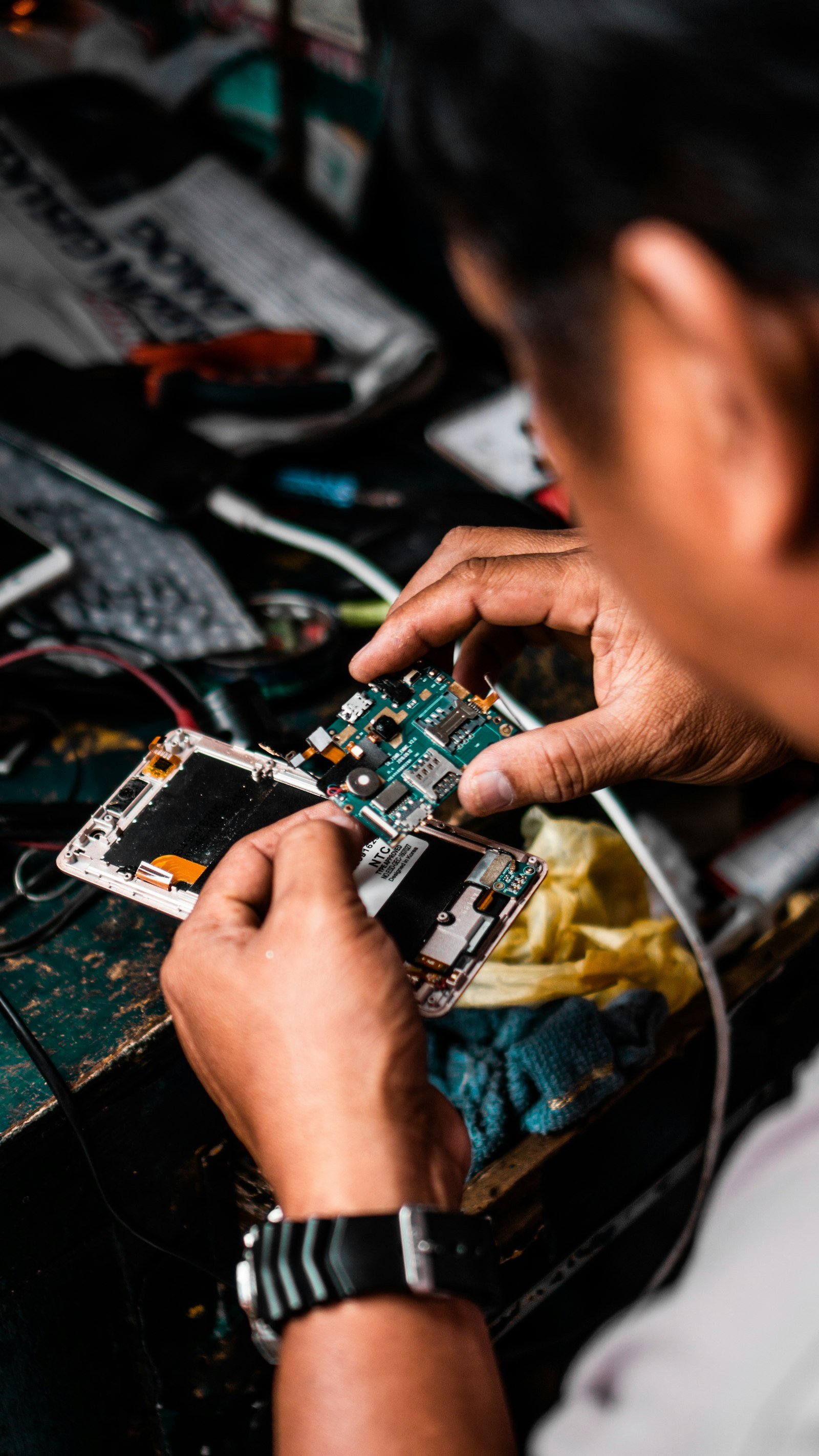 Technician repairing an Android smartphone on a bench.