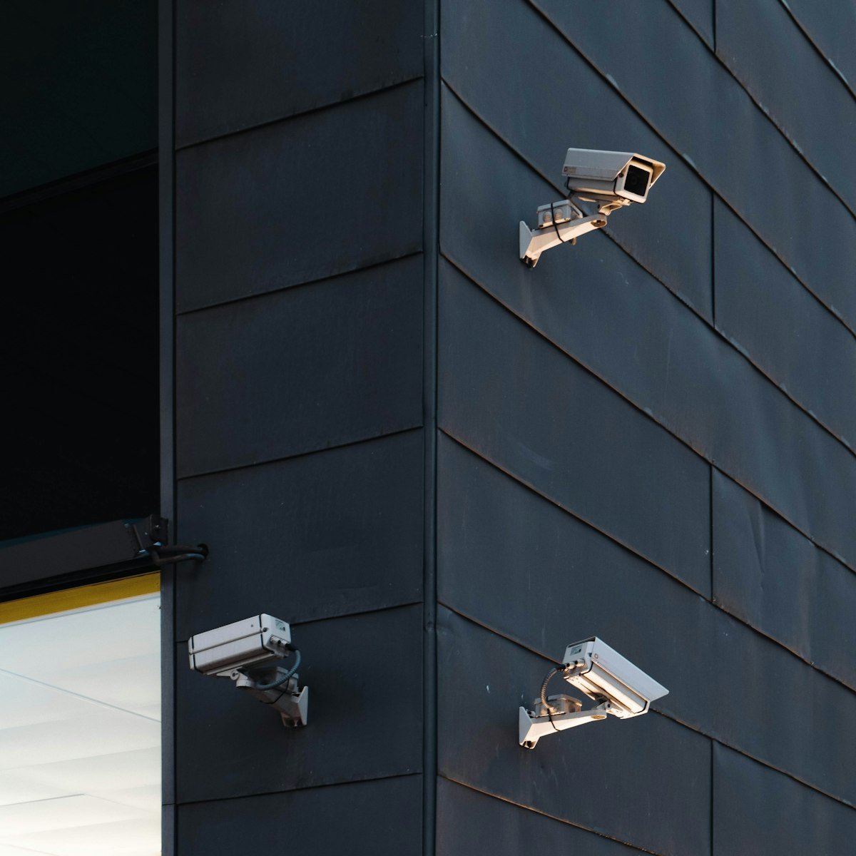 Three CCTV security cameras mounted on a commercial building wall.